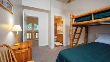A room with a bunk bed, a desk with a lamp, and a view of a balcony.