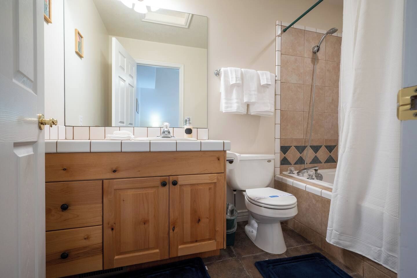 A bathroom with a wooden vanity, white sink, and a shower area.