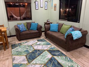 Un salon avec deux canapés marron, un tapis à motifs et une fenêtre donnant sur l’extérieur.