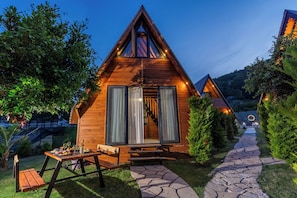 A wooden cabin with a triangular roof, a staircase leading to the entrance, and a stone pathway. - Karaöz Sapphire Bungalows (Kumluca)