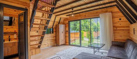 A cozy wooden cabin with a loft bedroom, a dining area, and a large sliding glass door to the backyard.