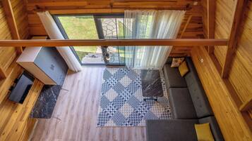 A wooden cabin interior with a sofa, a dining table, and a TV.