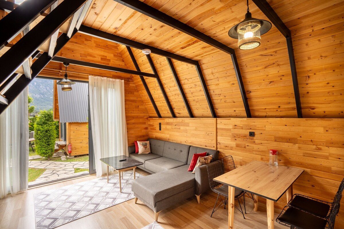 Ein gemütliches Holzinterieur mit einer Couch, einem Tisch und Blick ins Freie.