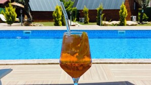 A glass of iced drink with a straw on a wooden table by a pool with mountains in the background. - Karaöz Sapphire Bungalows (Kumluca)