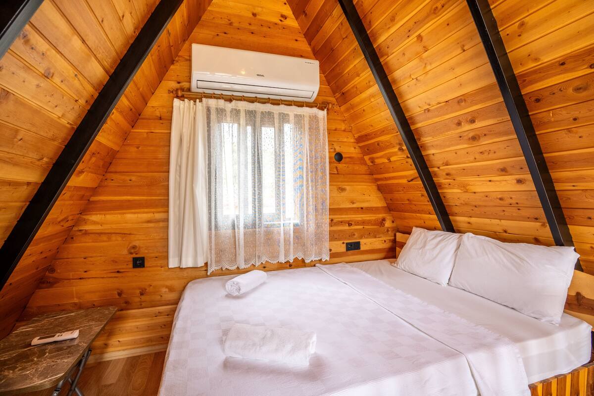 Quarto de cabana de madeira com cama, mesa e ar condicionado.
