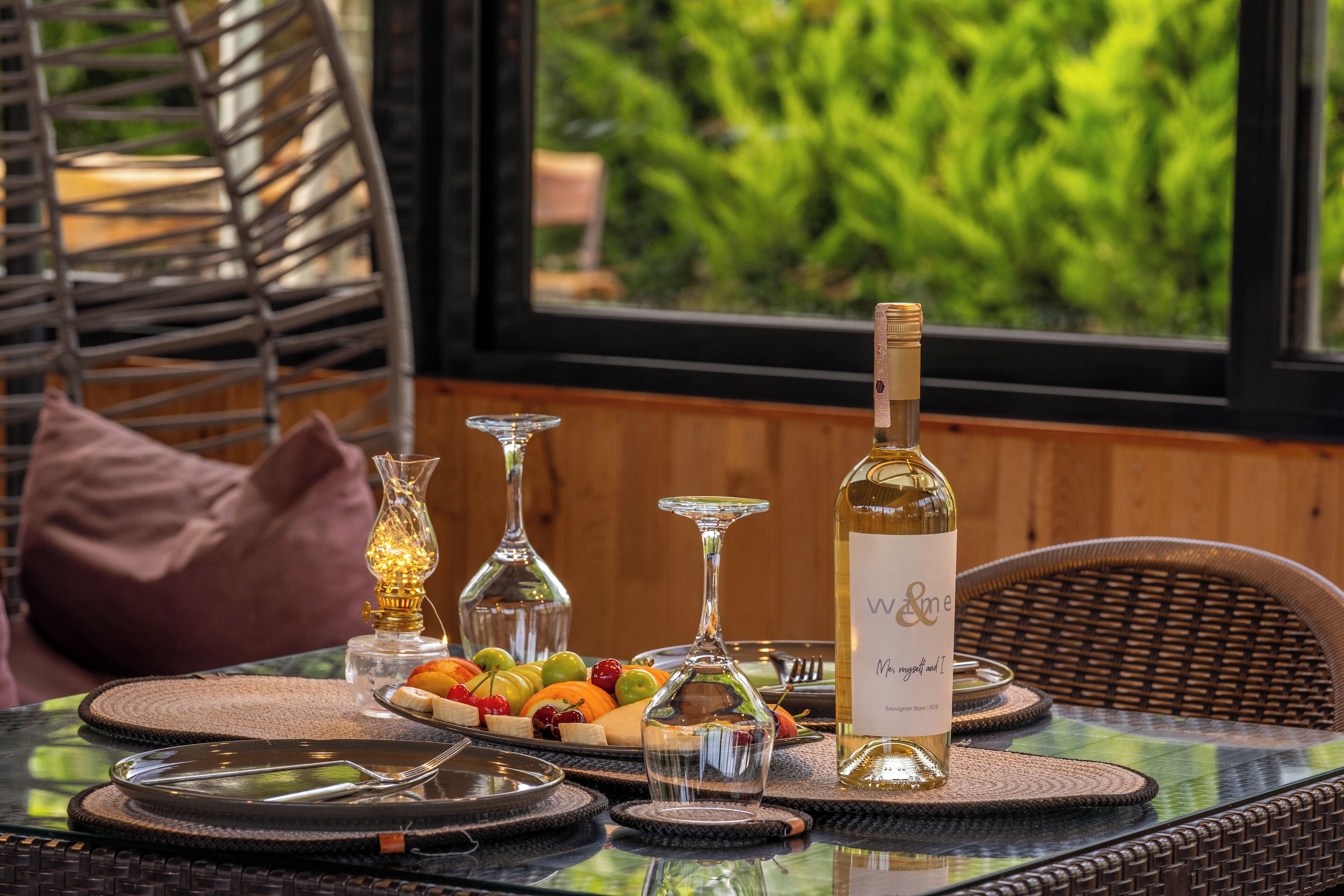 A dining table with a bottle of wine, fruit, and glasses.