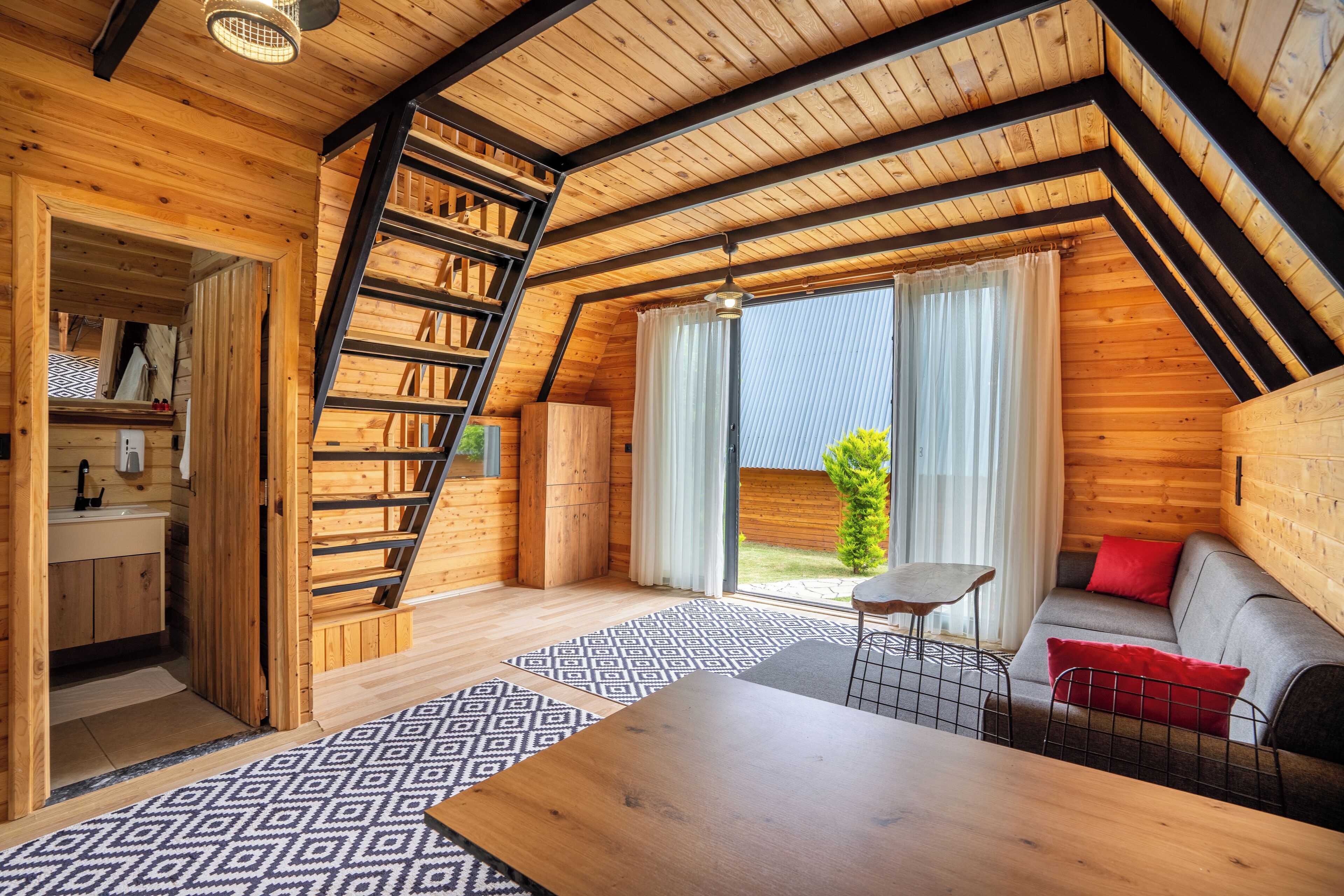 A cozy wooden cabin with a loft bedroom, a dining area, and a small kitchen.