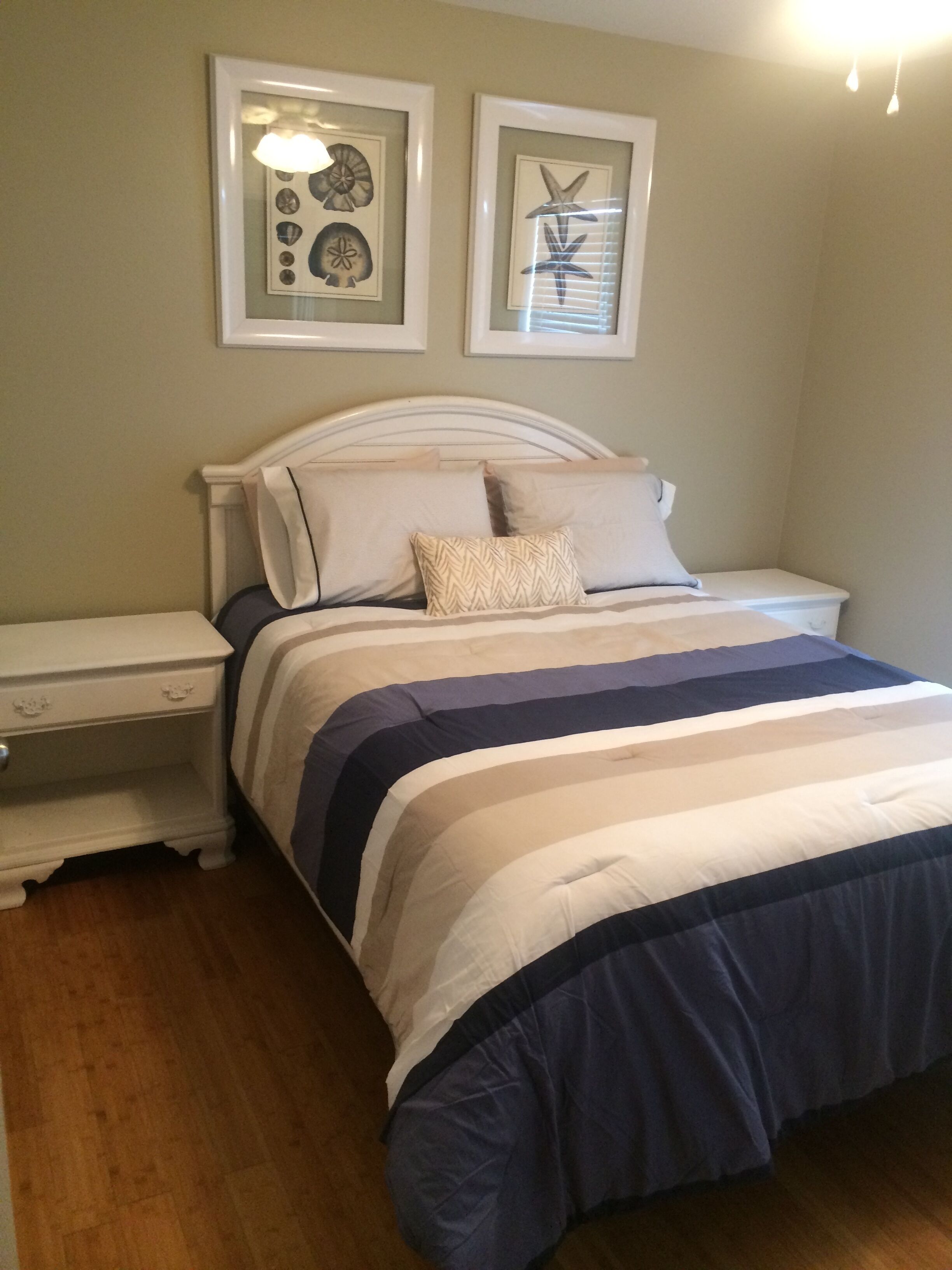 A bedroom with a bed, nightstands, a dresser, and two framed pictures on the wall.