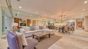 A modern living room with a sofa, coffee table, and dining area. - Beautiful New 3BR Condo at Indah (Puerto Vallarta)