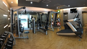 Ett gym med olika typer av träningsutrustning, inklusive löpband och styrketräningsmaskiner.