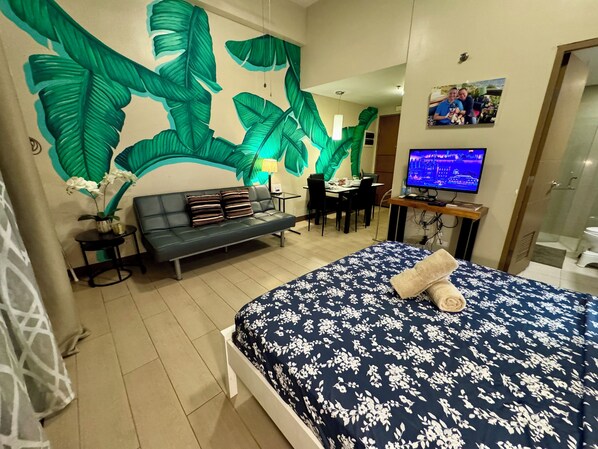 A hotel room with a bed, a sofa, a desk with a computer, and a TV. - Beautiful Corner Studio Near Resorts World Manila Across NAIA Terminal 3 (Pasay)