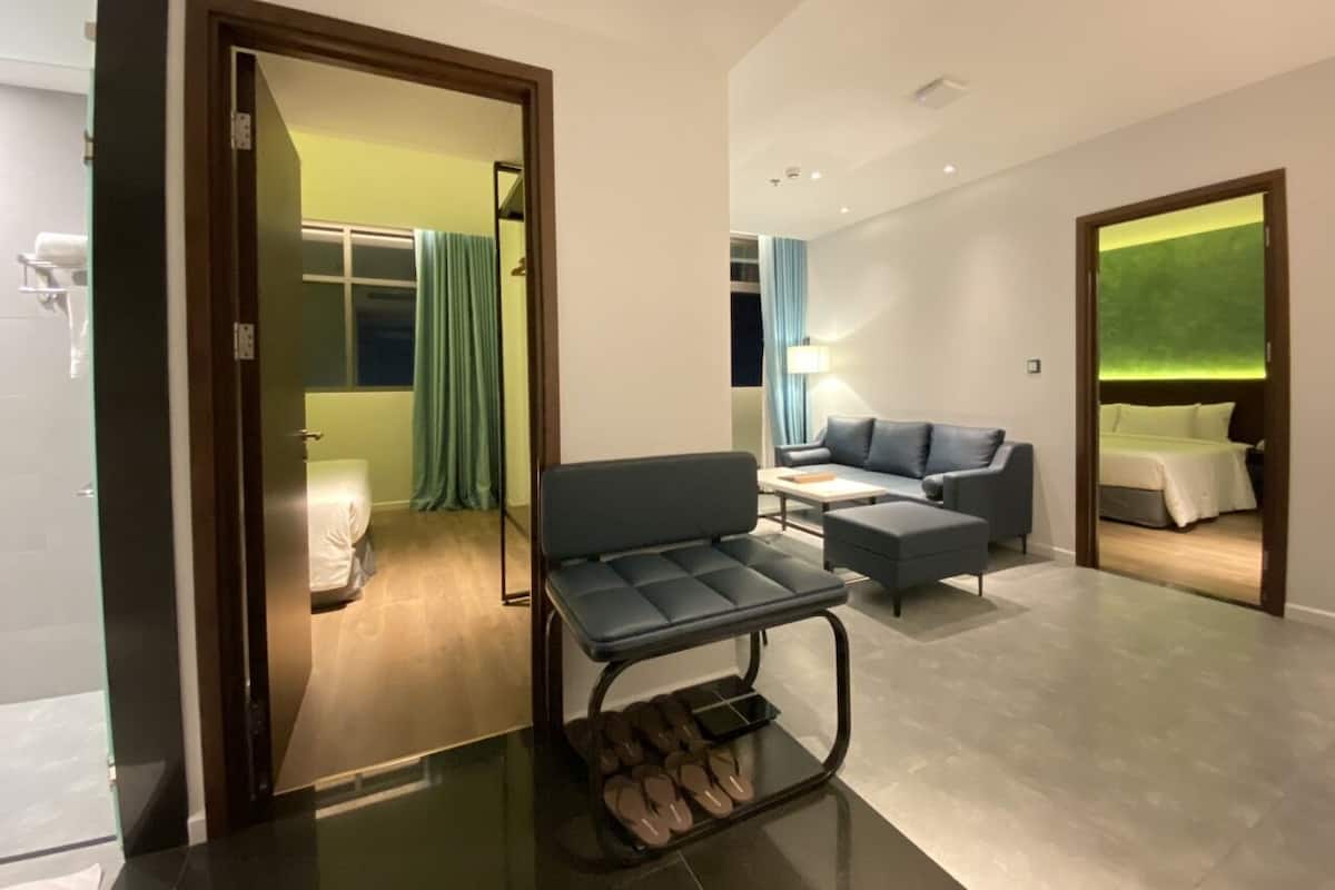 A modern hotel room with a sofa, a small table, and a shoe rack.