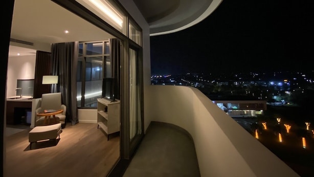 A modern hotel room with a balcony overlooking a cityscape at night. - NEWCC HOTEL & SERVICED APARTMENT (Truong Quang Trong)