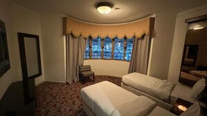A hotel room with two beds, a small table, and a window with curtains. - Sky View Hotel Madinah (Madinah)
