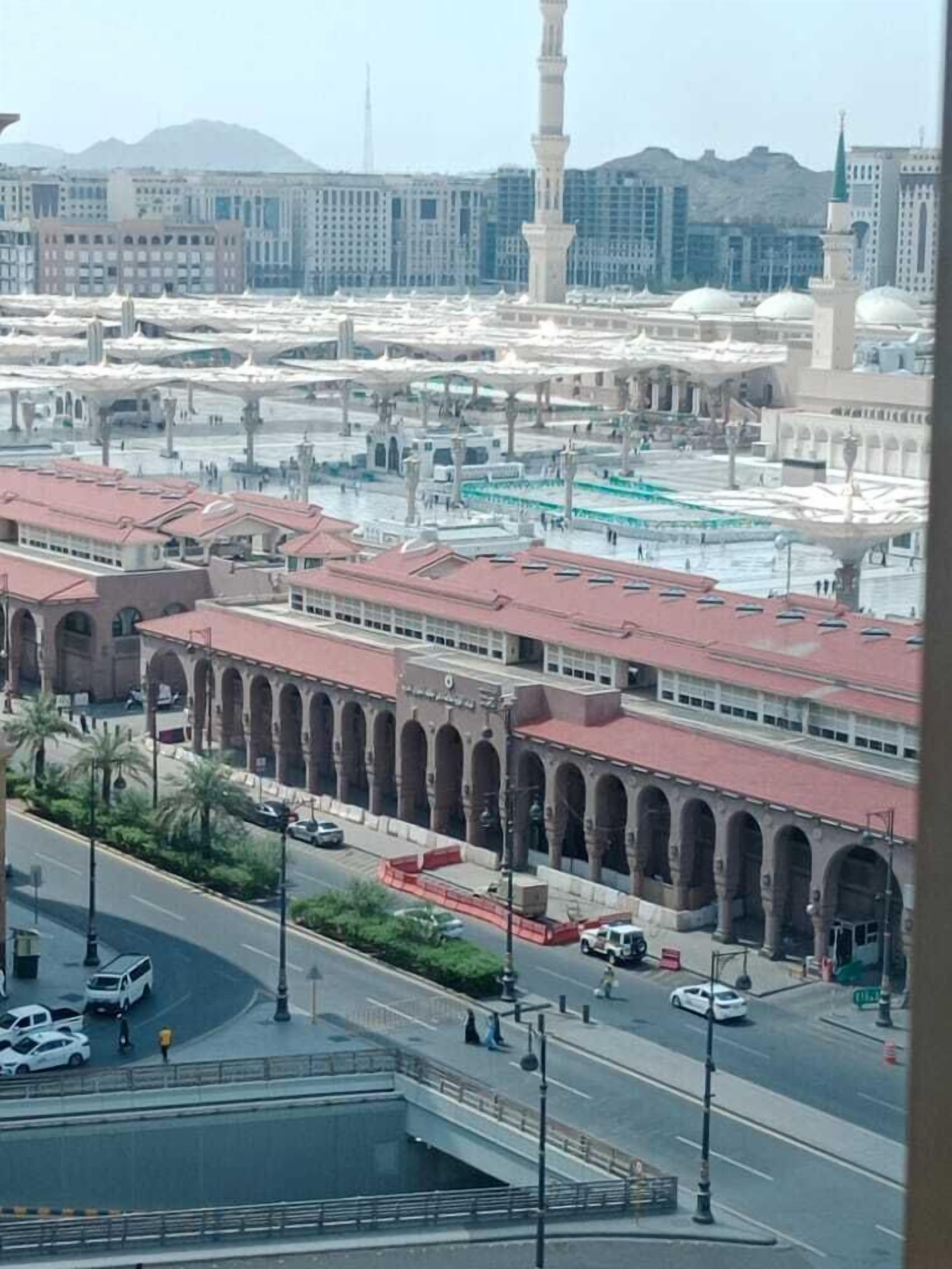 A view of a mosque with a large courtyard, minarets, and a prominent minaret.