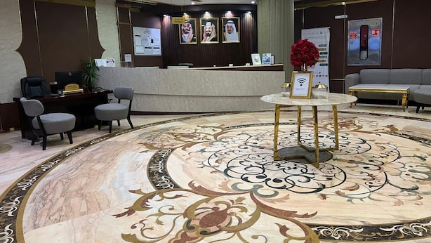 A lobby with a marble floor, reception desk, seating area, and a chandelier. - Sky View Hotel Madinah (Madinah)