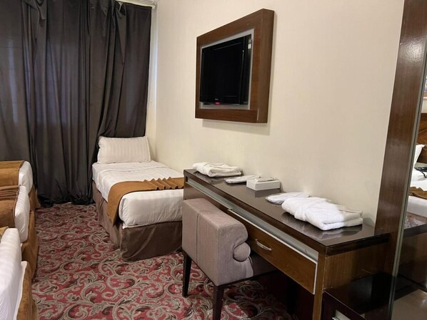 Una habitación de hotel con cama, escritorio, silla, televisor y espejo.