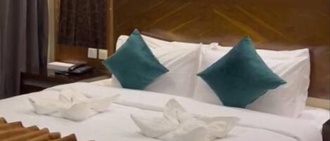 A neatly made bed with white linens, teal pillows, and a brown throw blanket.