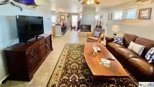 A spacious living room with a television, a ceiling fan, a coffee table, and a sofa.