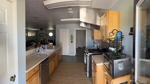 A compact kitchen with wooden cabinets, a built-in stove, and a microwave.