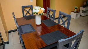 A dining table with a vase of flowers, surrounded by chairs. - 10 minutes to city centre!Family sized condo with swimming pool. (Nairobi)