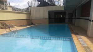Une piscine avec un escalier en métal et une terrasse carrelée.