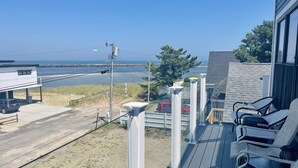 Eine Terrasse mit Sitzgelegenheiten, Blick auf den Strand und ein Parkplatz.