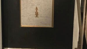 Un documento enmarco con texto manuscrito sobre una pared oscura.