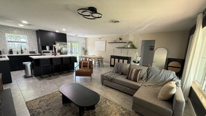 Ett modernt vardagsrum med en soffa, ett soffbord och en matplats med ett bord och stolar.