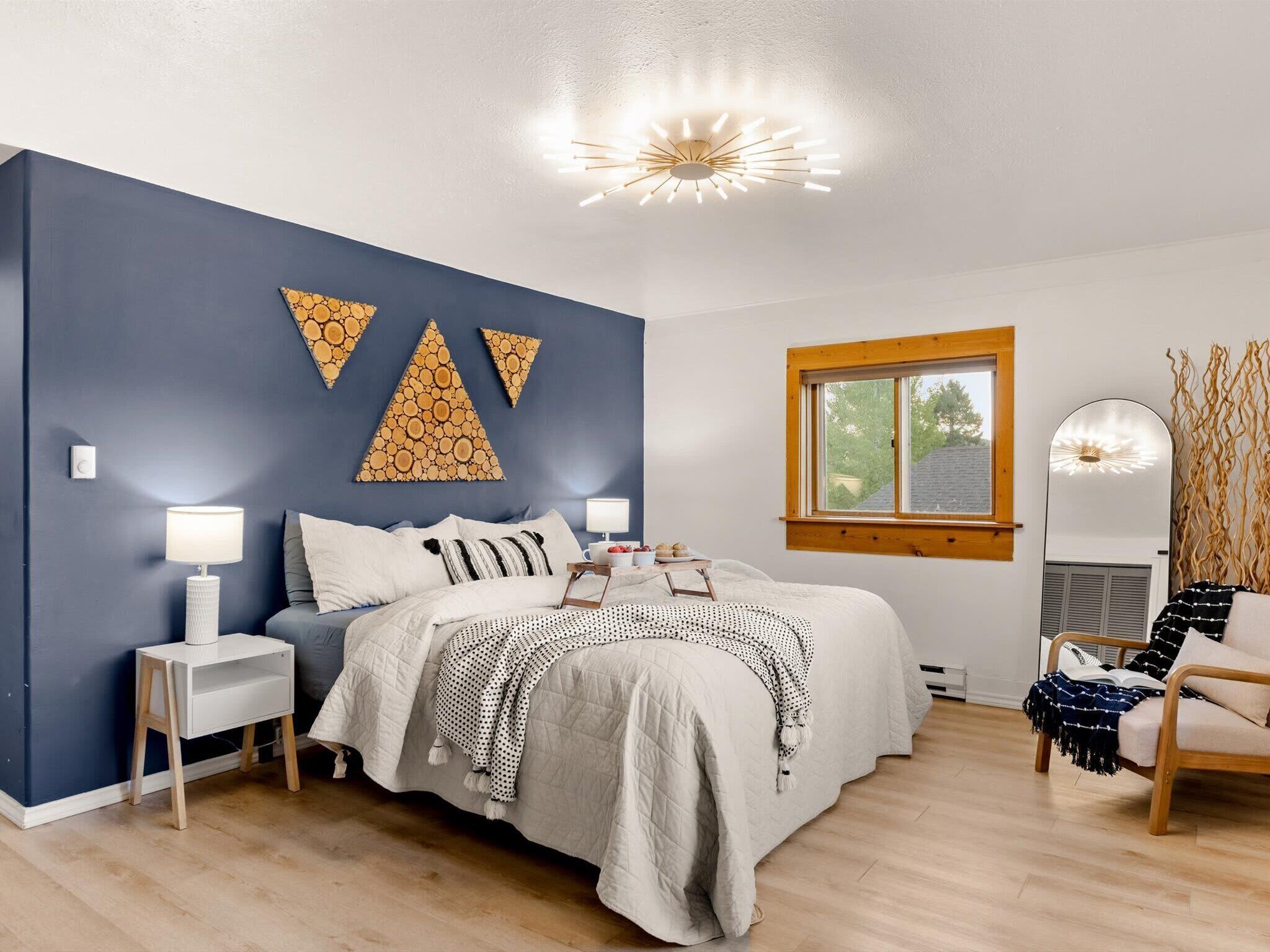 The master king suite, blue accent wall, wood slice art, and forest light coming through every window.
