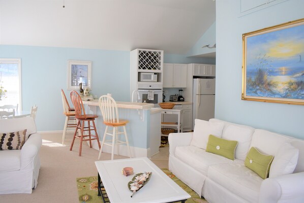 A compact living space with a kitchenette, a dining area, and a seating area with a white sofa and chairs.