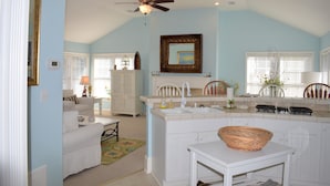 A spacious kitchen with white cabinetry, a central island, and a ceiling fan.