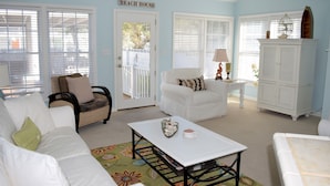 A living room with white furniture, a coffee table, and a cabinet.