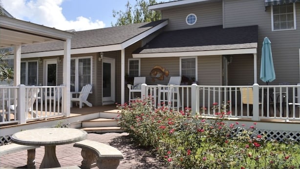 A house with a covered patio, outdoor seating, and a garden with flowers.