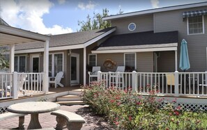 A house with a covered patio, outdoor seating, and a garden with flowers.