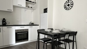 Cuina moderna amb armaris blancs, tauleig negre i zona de menjador amb taula i cadires negres.