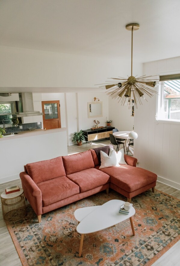 A modern living room with a sectional sofa, a small white coffee table, and a patterned rug.