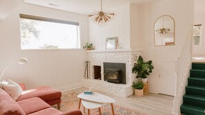 A living room with a white fireplace, a pink sofa, a small table, and a staircase with green steps. - Beautiful cottage w/pool in bamboo forest! (Central Point)