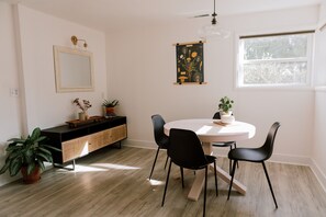 A dining area with a round table, black chairs, a wooden cabinet, and a potted plant.