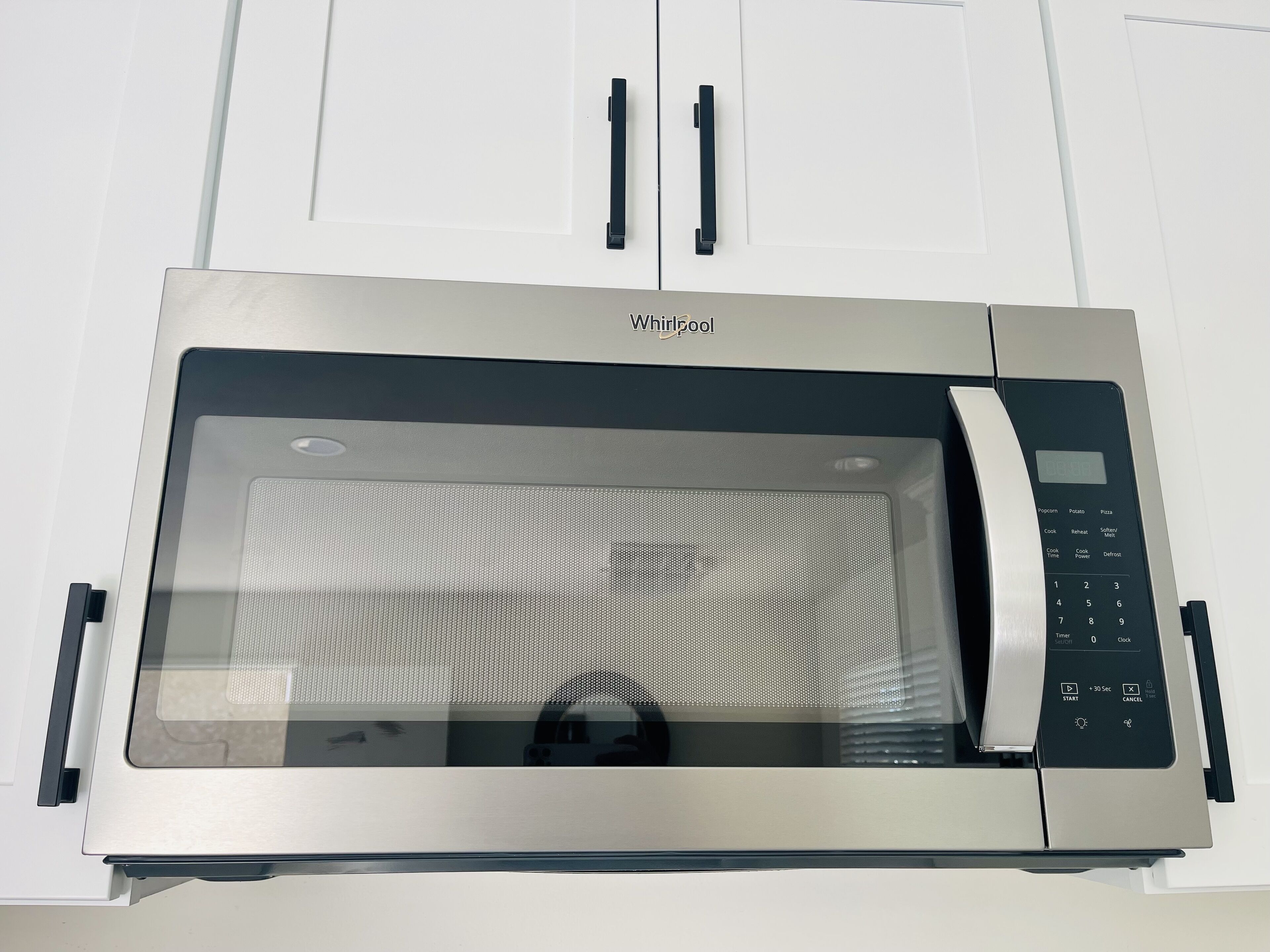 Un horno microondas Whirlpool con pantalla digital, panel de control y puerta de vidrio.