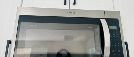 Un horno microondas Whirlpool con pantalla digital, panel de control y puerta de vidrio.