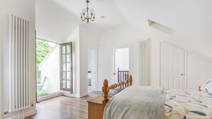 A bedroom with a bed, wooden headboard, and a view of the outdoors. - Ramblers, Marnhull, Shaftesbury (Marnhull)