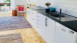 Een moderne keuken met witte kastjes, een zwart aanrecht en een geïntegreerde vaatwasser.