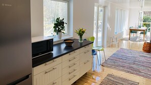 Een moderne keuken met een inbouwmagnetron, een groot raam en een eethoek met een tafel en stoelen.