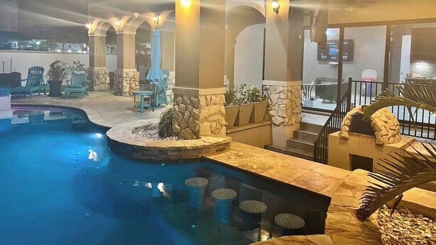 An indoor swimming pool with stone pillars, a stone bench, and a staircase leading to an upper level. - 5909 Havana Dr: Private Pool/Large Back Yard (South Padre Island)