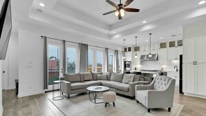 A spacious living room with a sectional sofa, a round coffee table, and a ceiling fan. - 5909 Havana Dr: Private Pool/Large Back Yard (South Padre Island)