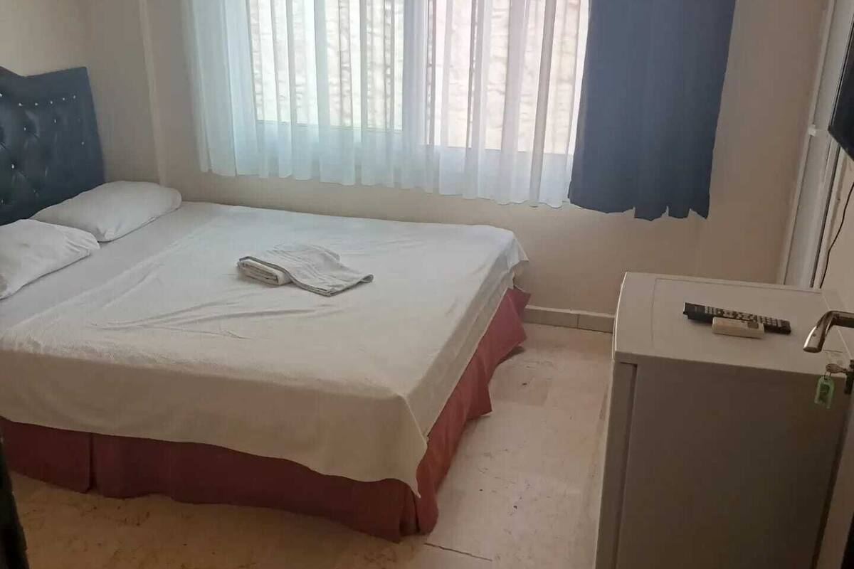 A hotel room with a bed, a desk, and a window with curtains.