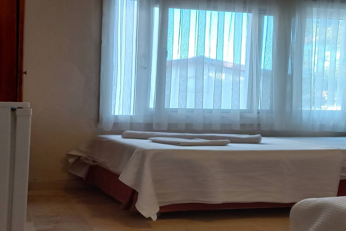 A room with a bed, a radiator, and a window with sheer curtains.