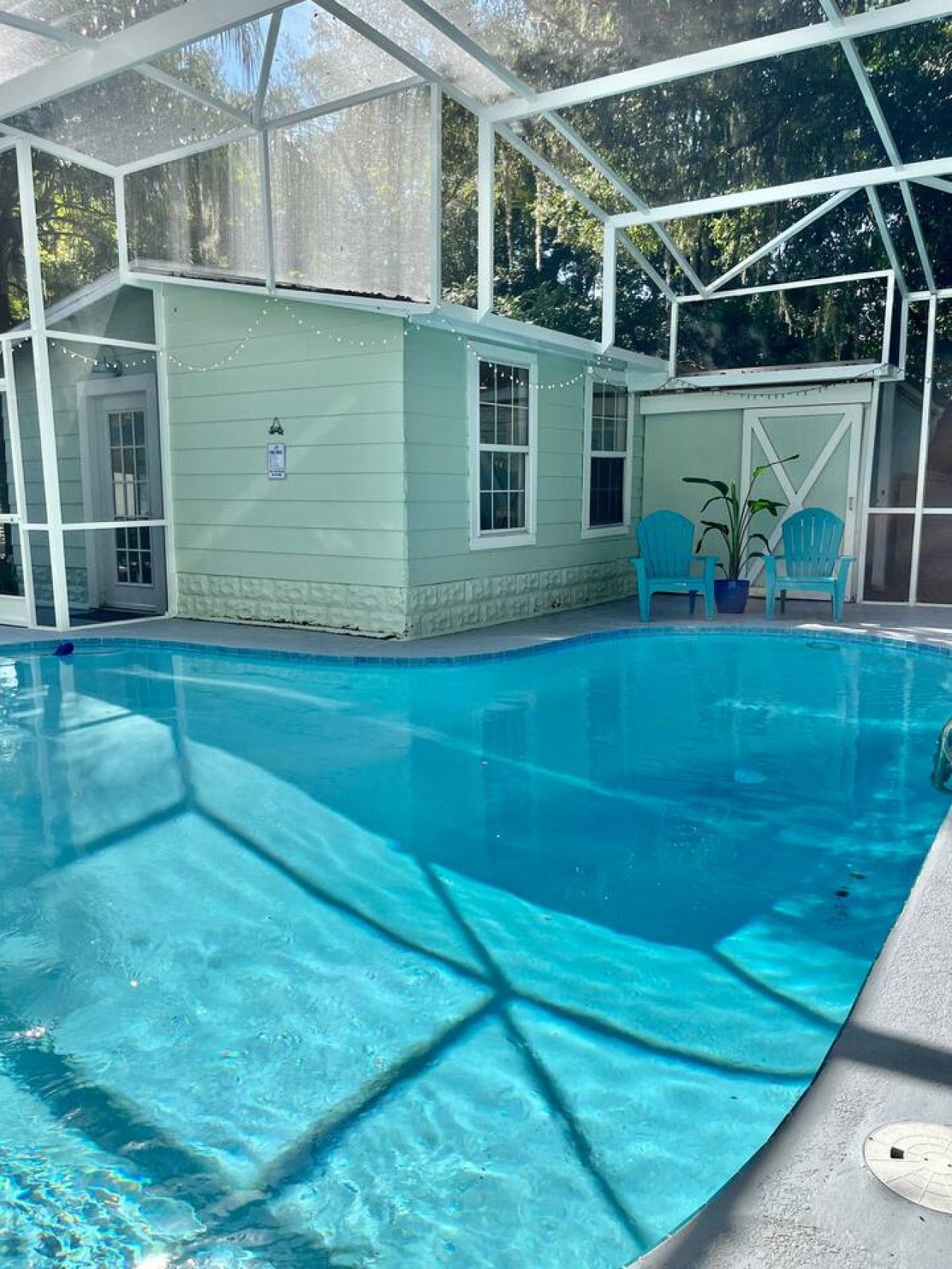 Ein klares, blaues Schwimmbecken mit überdachtem Bereich, einer Tür und zwei Stühlen.