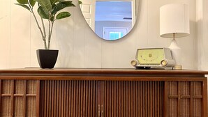 Eine Holzkonsole mit Spiegel, einer Topfpflanze und einem kleinen Tisch mit Lampe.